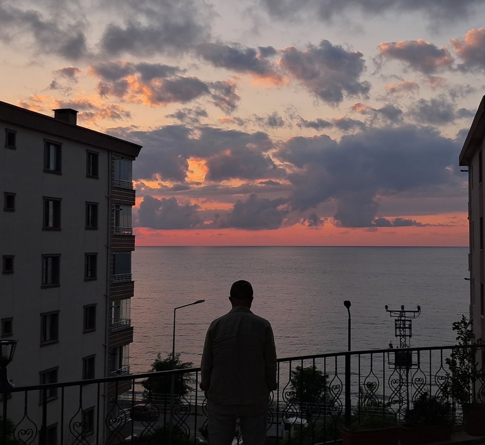 A man looking across the sea at sunset